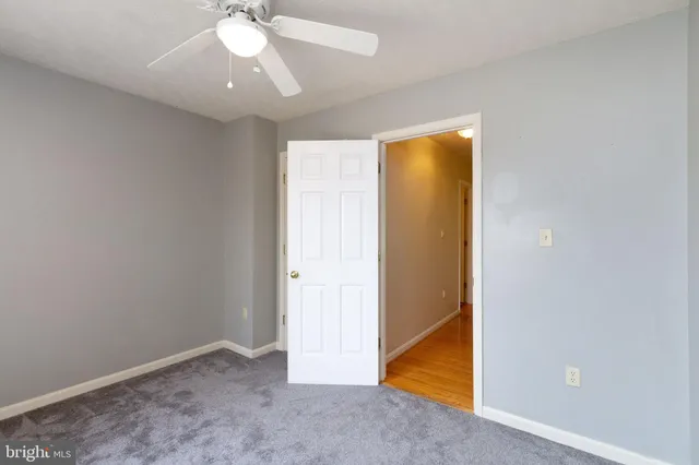 an empty room with a ceiling fan and carpet