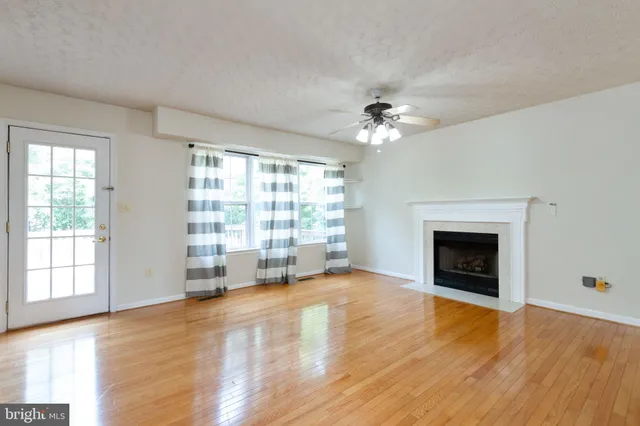 wooden floor fireplace and windows in an empty room