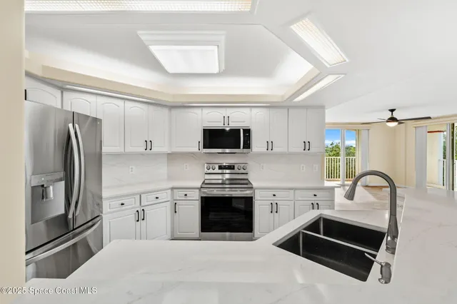 a kitchen with stainless steel appliances kitchen island granite countertop a refrigerator and a sink