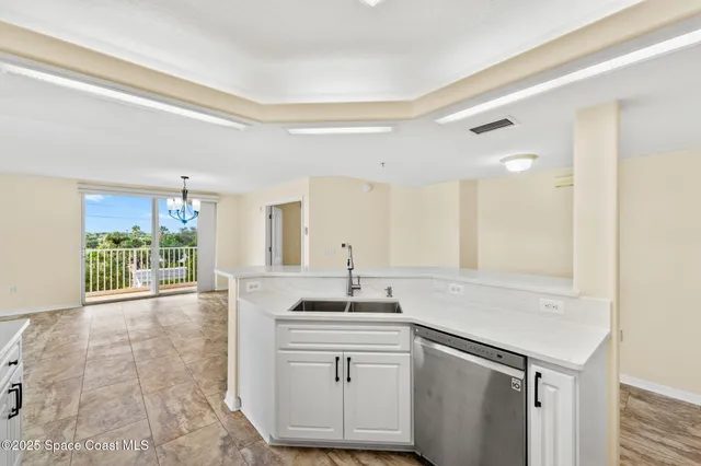 a kitchen with stainless steel appliances a stove a sink a microwave a refrigerator white cabinets and wooden floor