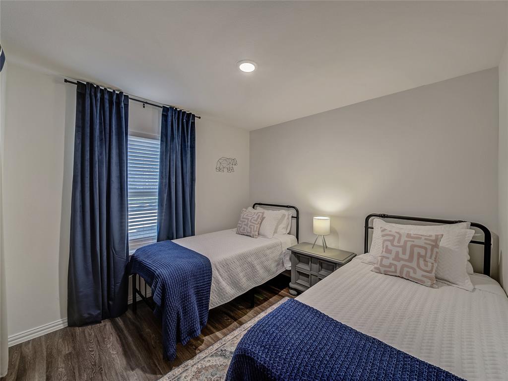 921 West 9th Street Bonham, TX 75418 - Photo 13 of 24 a bedroom with two beds and a large mirror