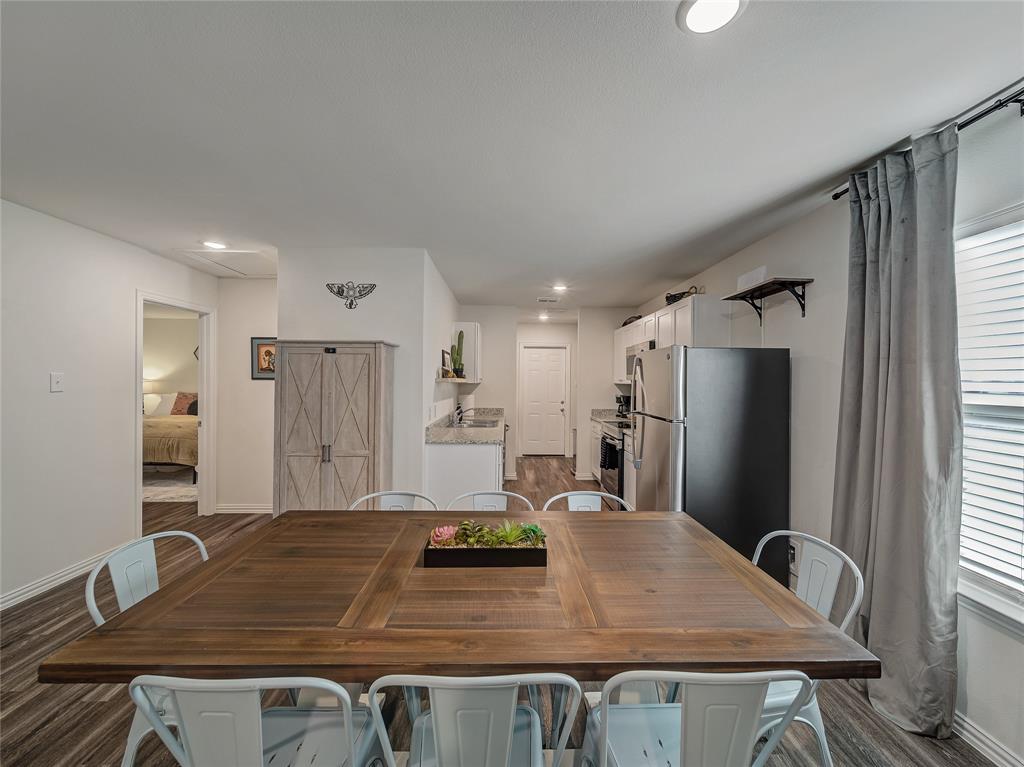 921 West 9th Street Bonham, TX 75418 - Photo 15 of 24 a kitchen with stainless steel appliances granite countertop a refrigerator a stove and white cabinets with wooden floor