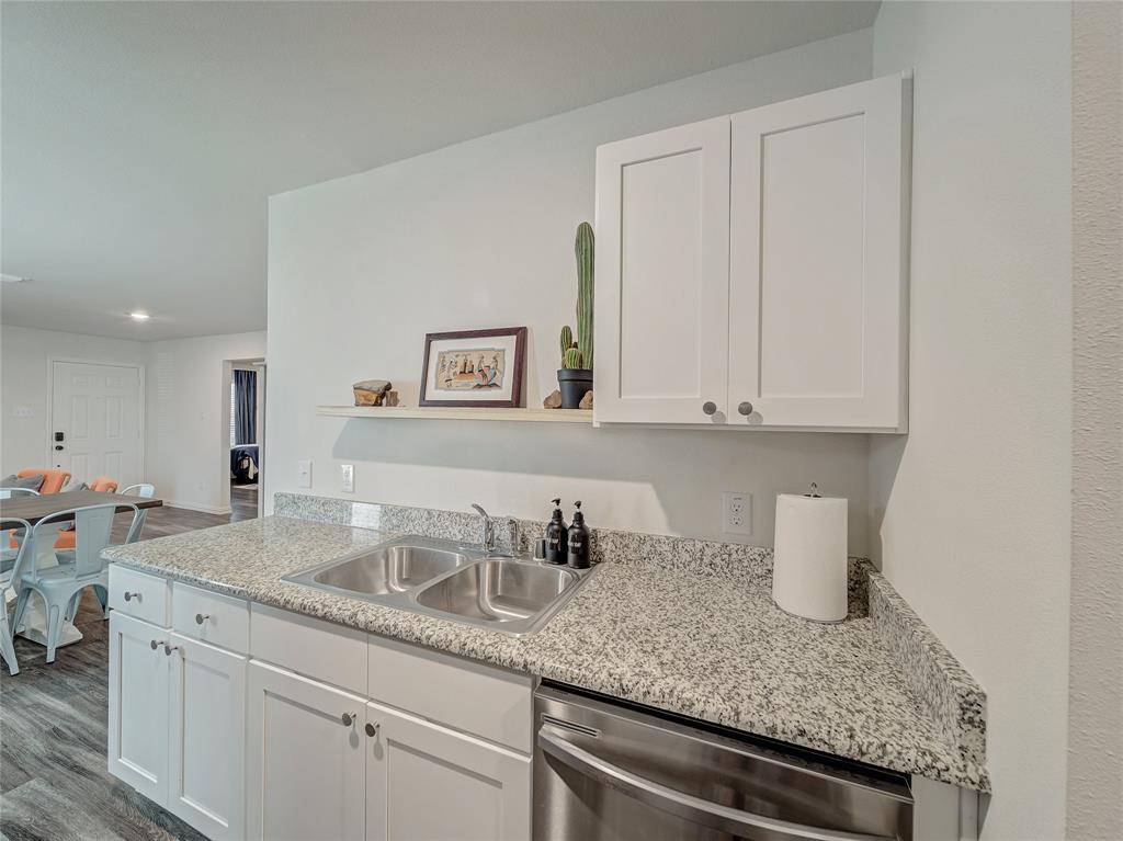 921 West 9th Street Bonham, TX 75418 - Photo 18 of 24 a kitchen with granite countertop white cabinets and a sink