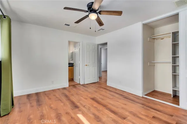 a view of empty room with wooden floor and ceiling fan