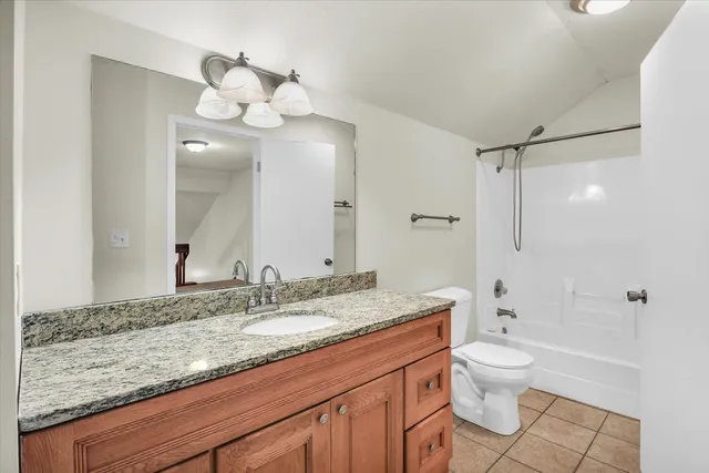 a bathroom with a granite countertop sink a toilet and bathtub