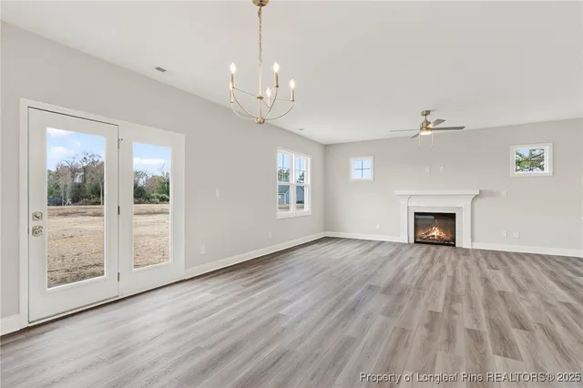 a view of an empty room with wooden floor fireplace and a window