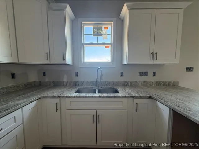 a kitchen with granite countertop cabinets sink and window