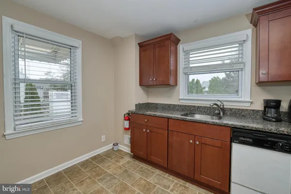 a kitchen with granite countertop a sink window and cabinets