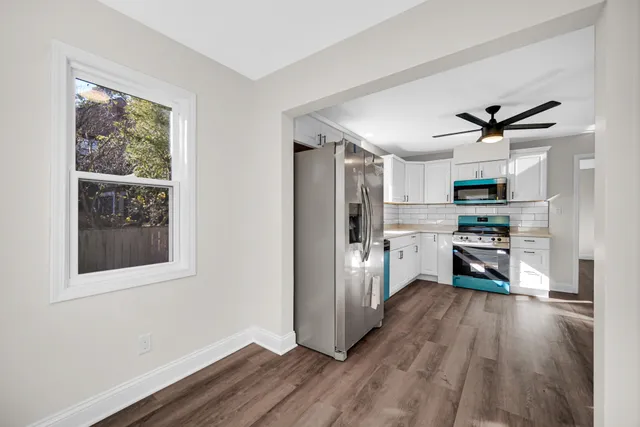 a kitchen with stainless steel appliances a refrigerator a stove top oven a sink with wooden floor and cabinets