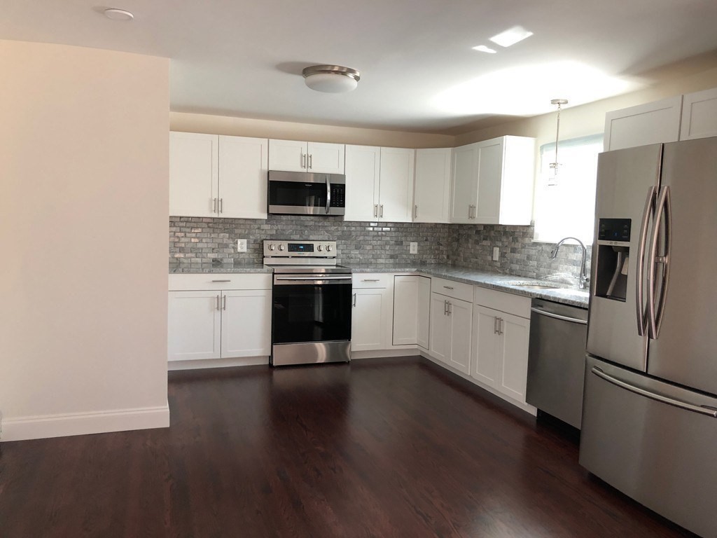101 Parker Road Lancaster, MA 01523 - Photo 11 of 35 a kitchen with stainless steel appliances granite countertop a stove top oven a sink a refrigerator white cabinets and wooden floor