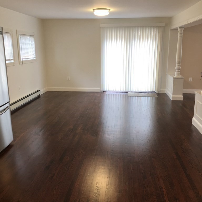 101 Parker Road Lancaster, MA 01523 - Photo 16 of 35 an empty room with wooden floor and windows with curtains