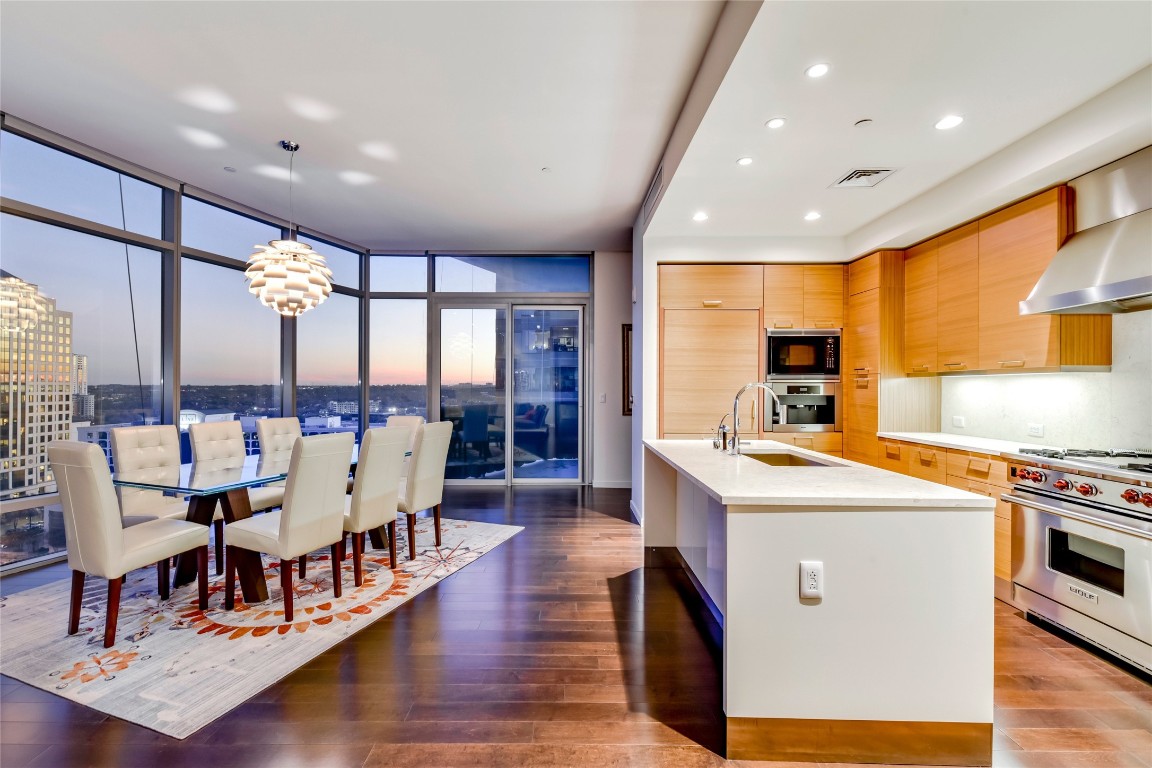 a living room with stainless steel appliances kitchen island granite countertop a table chairs and a view of living room