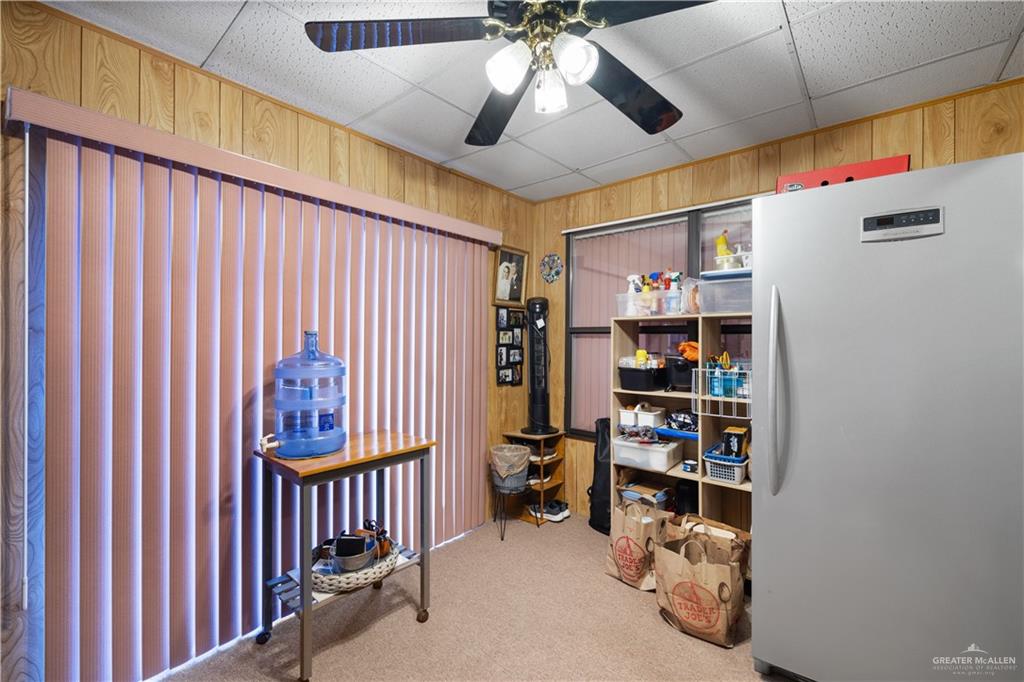 1804 Woodrow Street, Unit 184 Mission, TX 78572 - Photo 11 of 15 Misc room featuring wood walls, light colored carpet, a paneled ceiling, and a ceiling fan