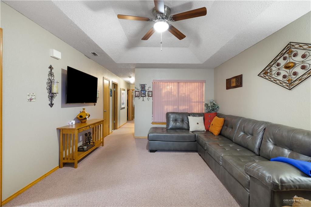 1804 Woodrow Street, Unit 184 Mission, TX 78572 - Photo 4 of 15 Living area featuring a textured ceiling, carpet flooring, a tray ceiling, and ceiling fan