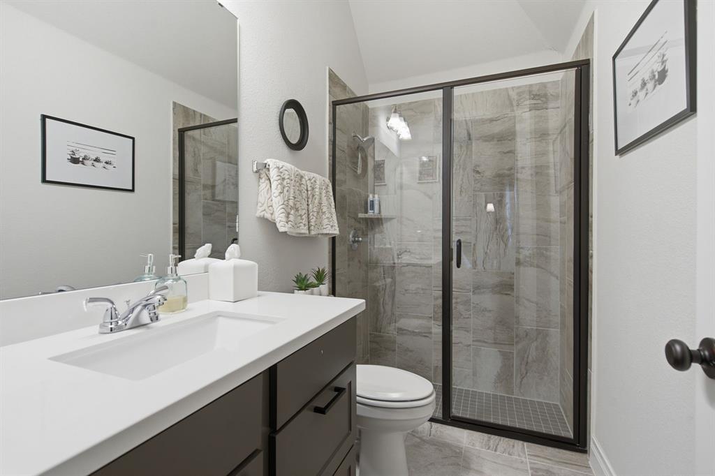 904 Fallbrook Avenue Denton, TX 76210 - Photo 25 of 30 a bathroom with a shower sink vanity mirror and toilet