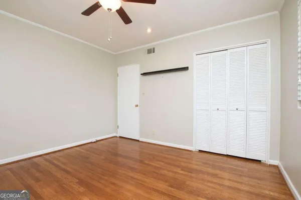 an empty room with wooden floor ceiling fan and window