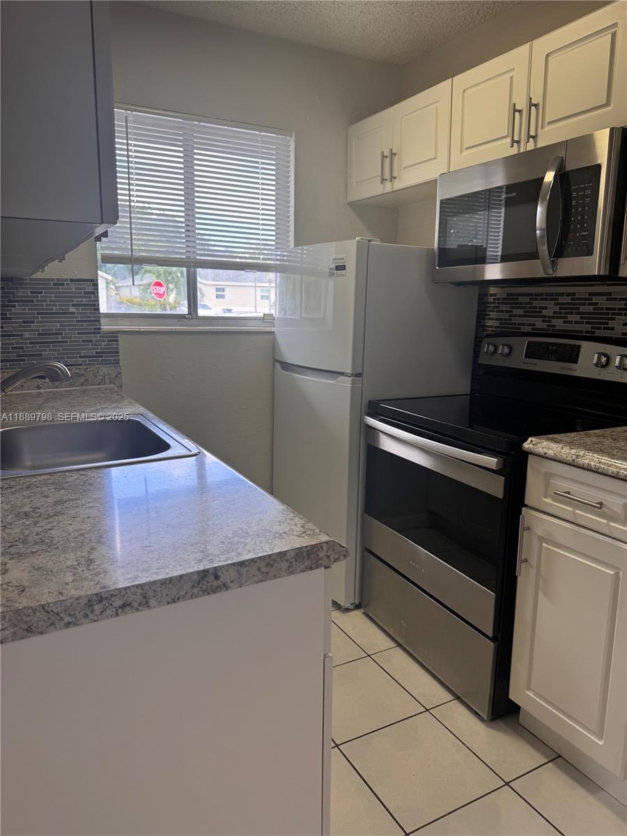 2150 Madison Street, Unit 20 Hollywood, FL 33020 - Photo 2 of 9 a kitchen with stainless steel appliances a stove microwave and sink