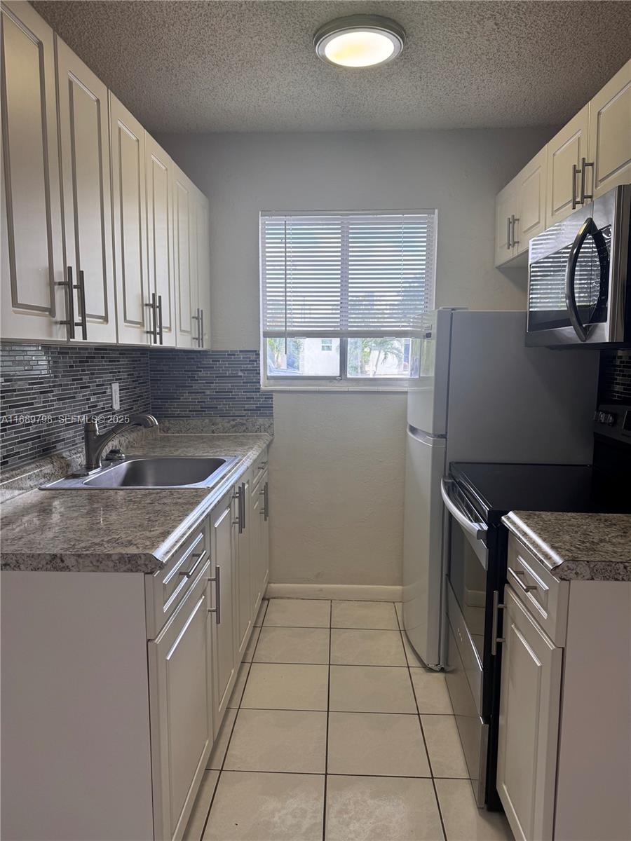 2150 Madison Street, Unit 20 Hollywood, FL 33020 - Photo 3 of 9 a kitchen that has a sink and a stove