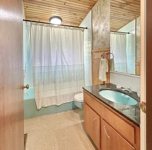 a bathroom with a granite countertop sink a toilet and shower