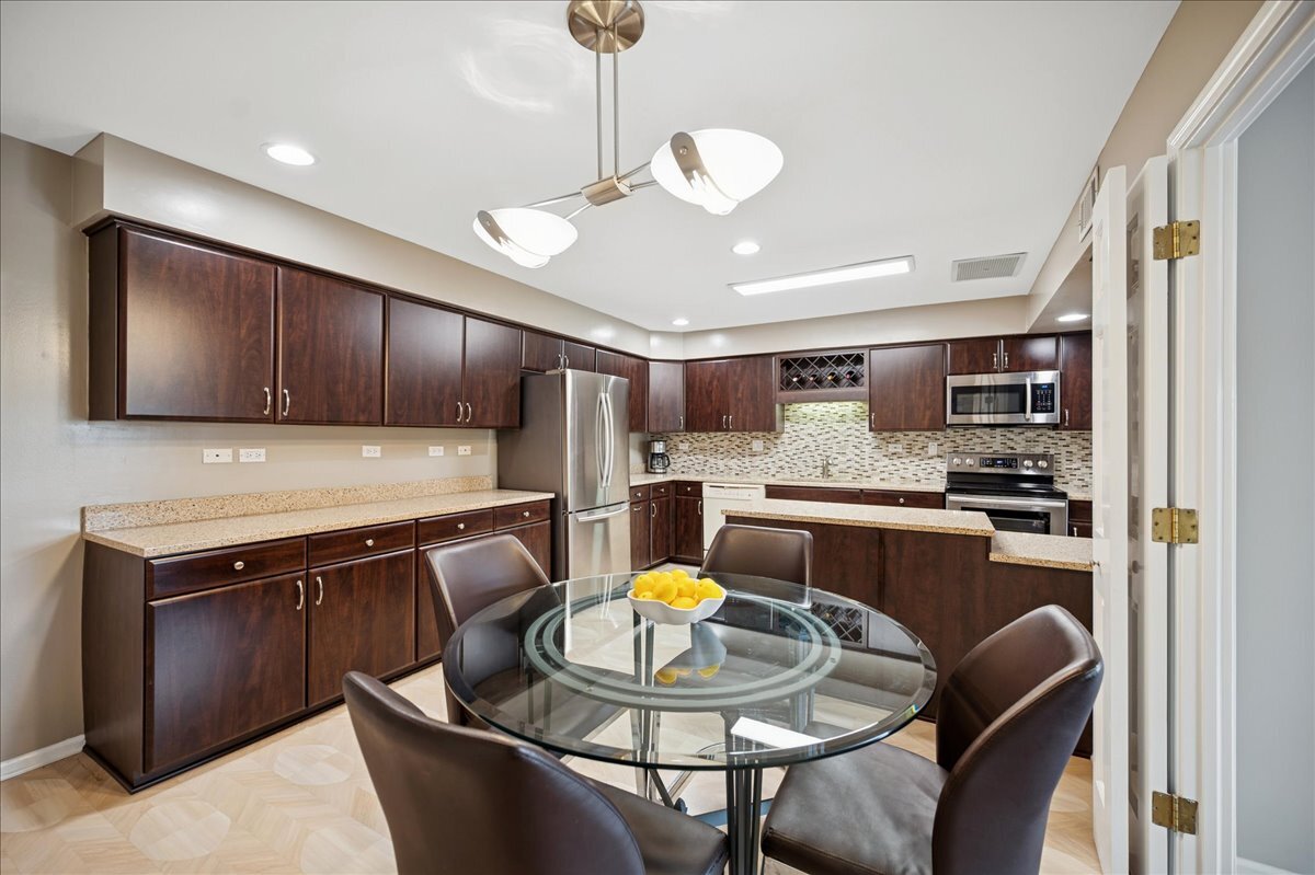 3741 Mission Hills Road, Unit 209 Northbrook, IL 60062 - Photo 9 of 18 a kitchen with stainless steel appliances granite countertop a stove a sink dishwasher a dining table and chairs with wooden floor