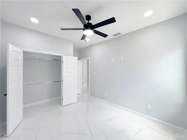 an empty room with closet and ceiling fan
