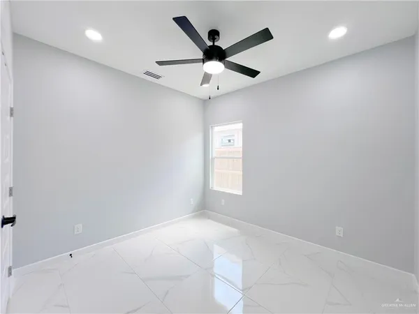 an empty room with ceiling fan and window