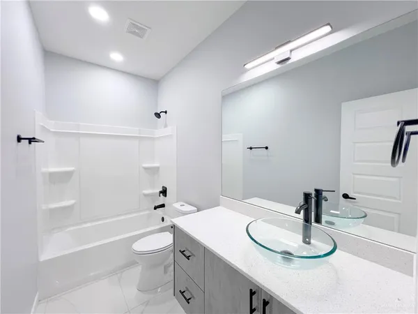 a bathroom with a granite countertop sink a toilet and a large mirror
