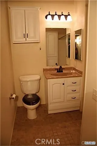 a bathroom with a granite countertop toilet sink and mirror