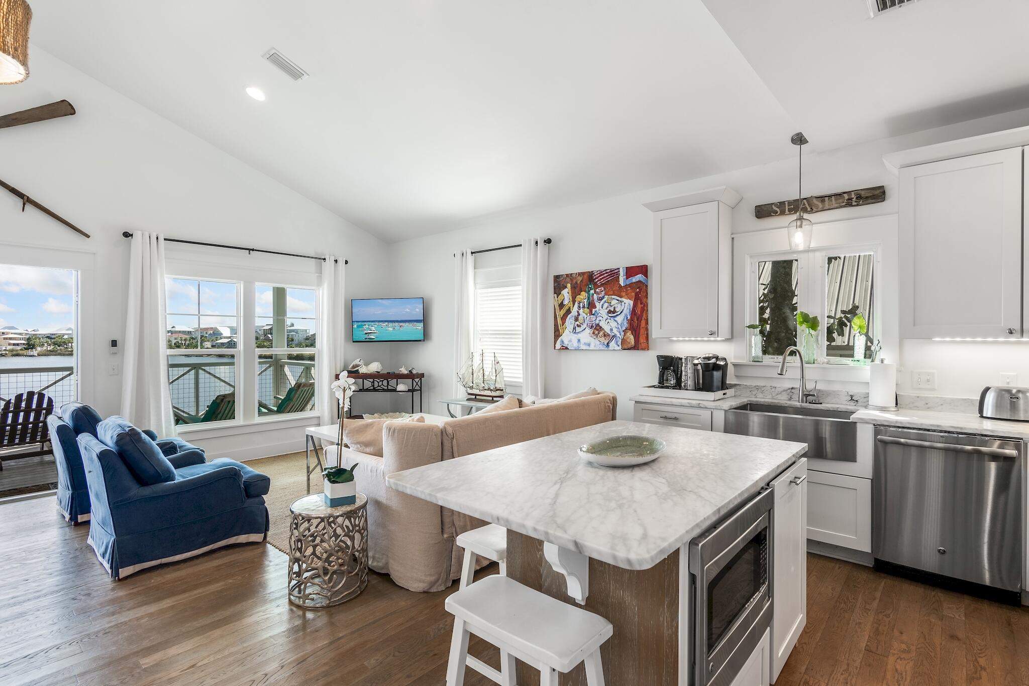 301 South Gulf Drive Santa Rosa Beach, FL 32459 - Photo 11 of 26 a open kitchen with stainless steel appliances granite countertop a kitchen island hardwood floor sink stove dining table and chairs