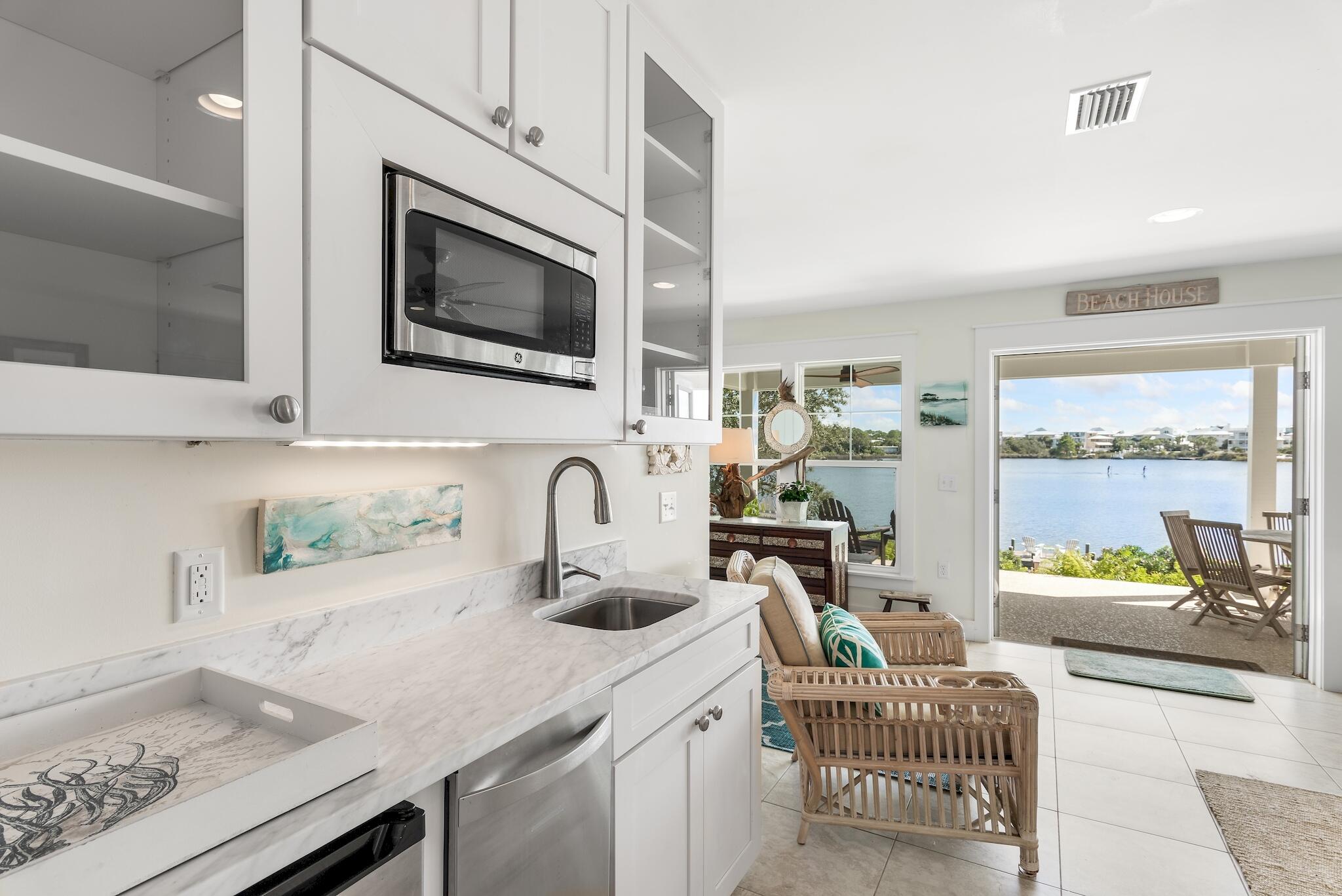 301 South Gulf Drive Santa Rosa Beach, FL 32459 - Photo 5 of 26 a kitchen with a sink a microwave a stove and white cabinets with wooden floor