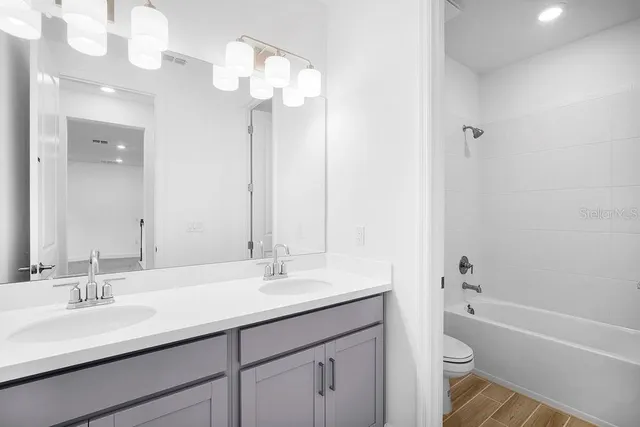 a bathroom with a double vanity sink mirror toilet and bathtub
