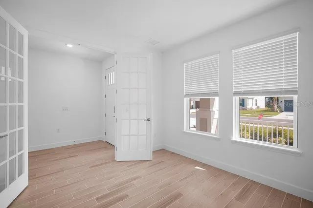 a view of an empty room with wooden floor and a window