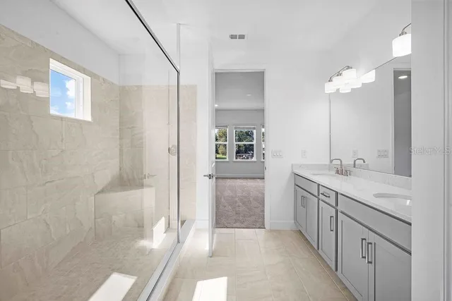 a spacious bathroom with a granite countertop sink a mirror and a shower