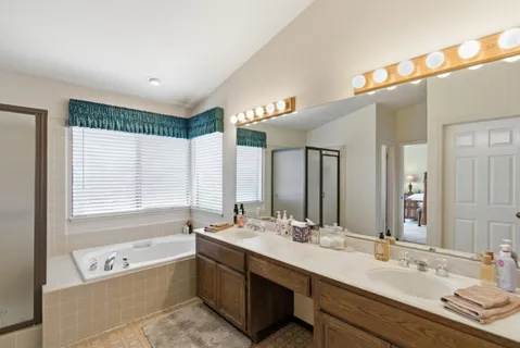a bathroom with a tub a double vanity sink and mirror