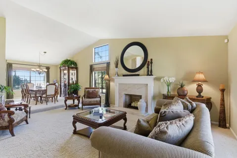a living room with furniture a fireplace and a floor to ceiling window