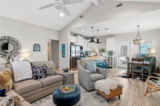 a living room with furniture kitchen view and a chandelier
