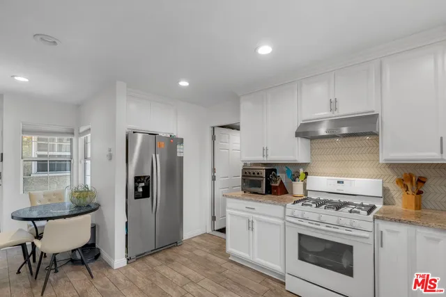 a kitchen with stainless steel appliances a stove a refrigerator and a white cabinets