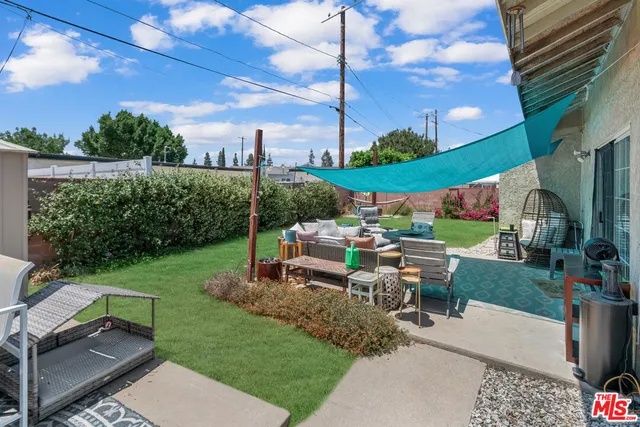 a view of a patio with couches table and chairs with plants and a yard