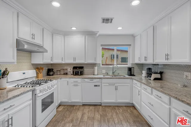 a kitchen with granite countertop white cabinets and white appliances