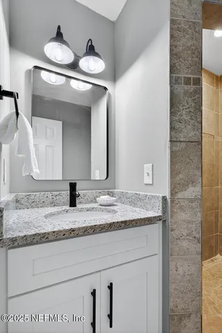 a bathroom with a granite countertop sink and a mirror