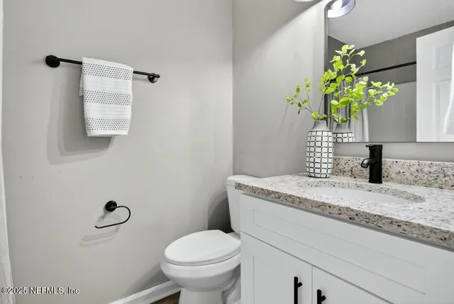 a bathroom with a granite countertop toilet a sink and a mirror
