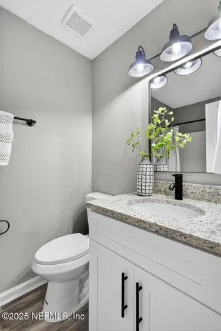 a bathroom with a granite countertop sink a toilet and a mirror