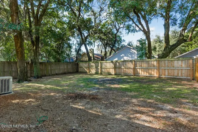 a view of a yard with wooden fence and a large tree
