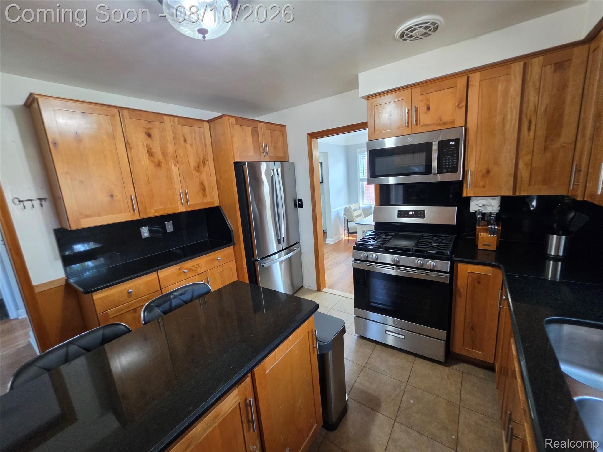 31159 Kelly Road Fraser, MI 48026 - Photo 7 of 13 Kitchen featuring wood cabinetry, black countertops, stainless steel appliances, and tile flooring