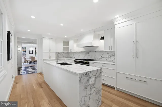 a kitchen with a sink a stove a refrigerator and white cabinets with wooden floor