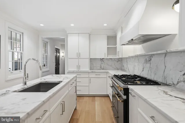 a kitchen that has a sink a stove and cabinets