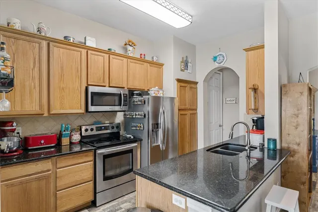 a kitchen with stainless steel appliances granite countertop a sink a stove and a refrigerator with wooden floor