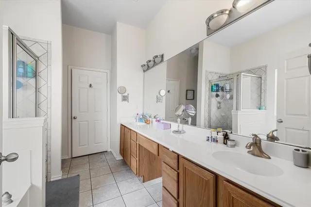a bathroom with a sink double vanity granite tub shower and a mirror