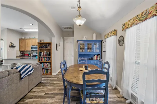 a living room with furniture and a dining table with wooden floor