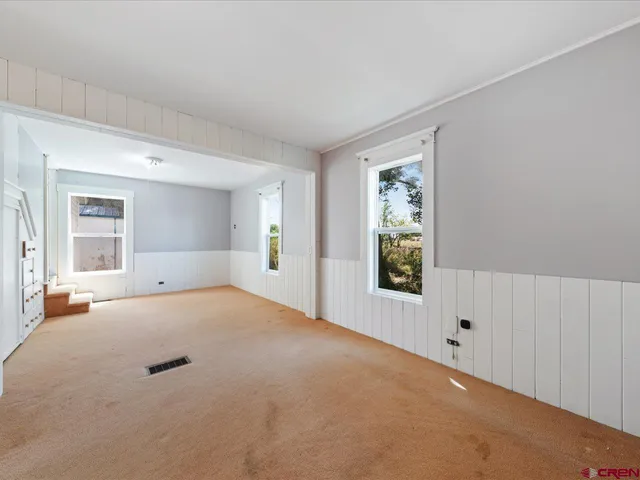 a view of an empty room with window and wooden floor